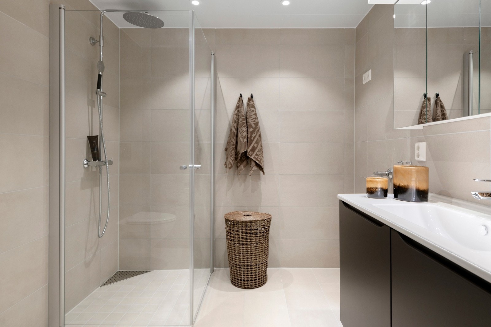 Flislagt og elegant bad med stor dusj, WC, innredning og opplegg til vaskemaskin. Galleribilde