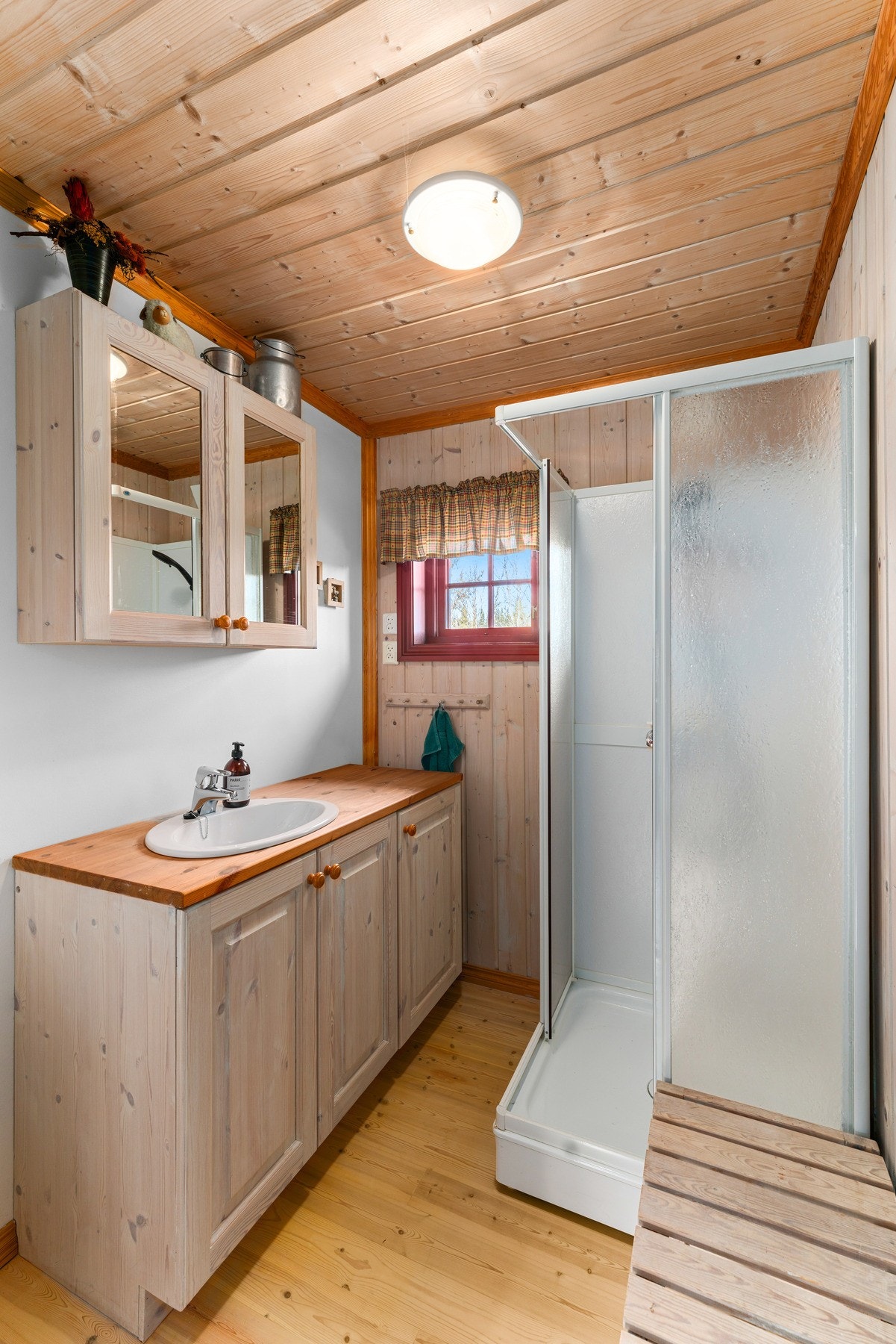 Det praktiske hyttebadet har tregulv, panelte vegger og malte plater i himlingen. Her finner du servant med underskap, speilskap, dusjkabinett og naturlig avtrekk. Galleribilde