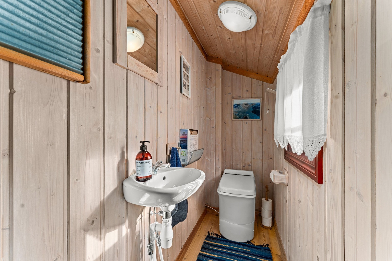 Fra entreen er det adkomst til et praktisk toalettrom med forbrenningstoalett, tregulv, panel på vegger og himling, samt servant, speil og naturlig avtrekk - alt i enkel og funksjonell stil. Galleribilde