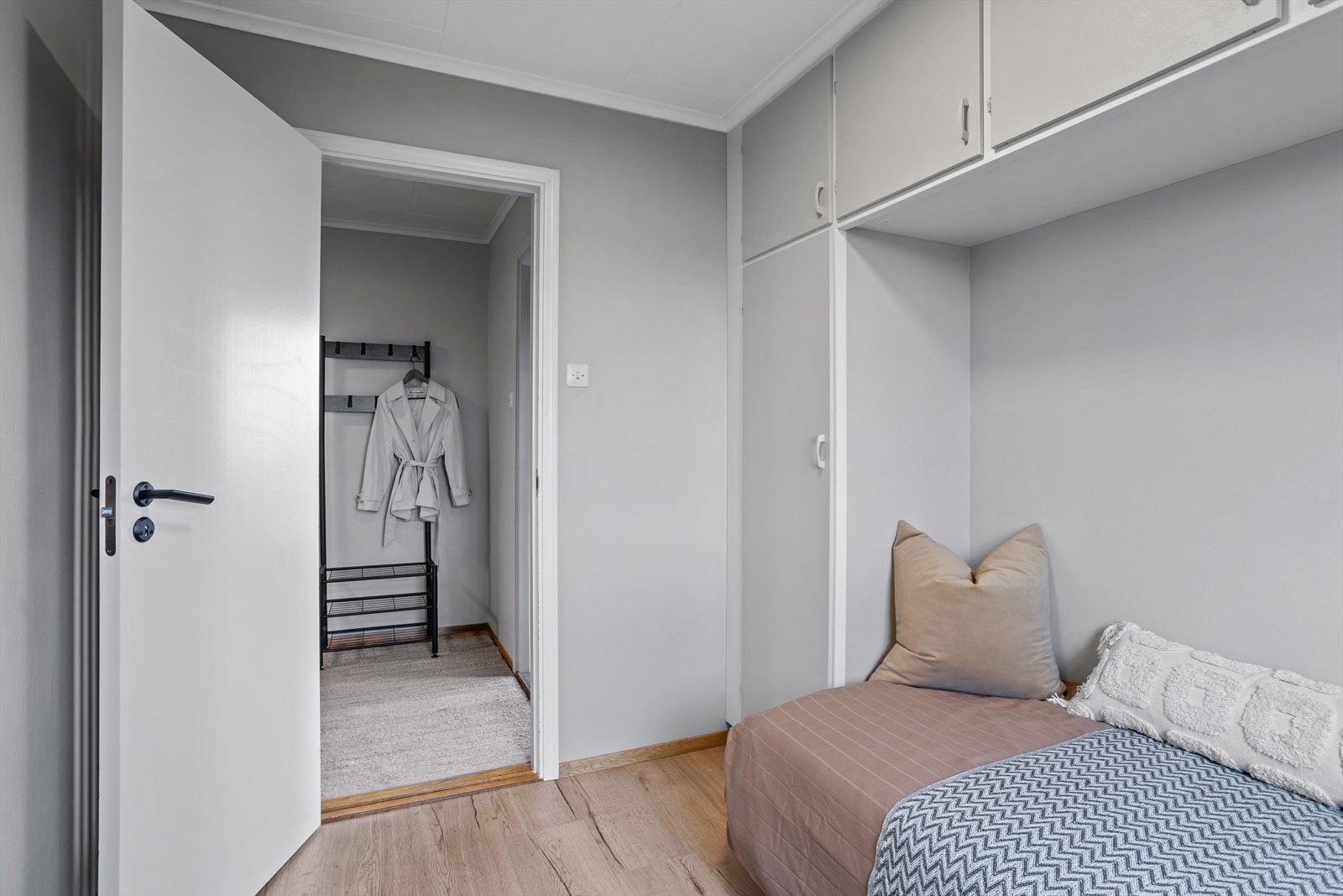Rommet er malt i en fin gråtone, og døren har et moderne svart håndtak. Galleribilde