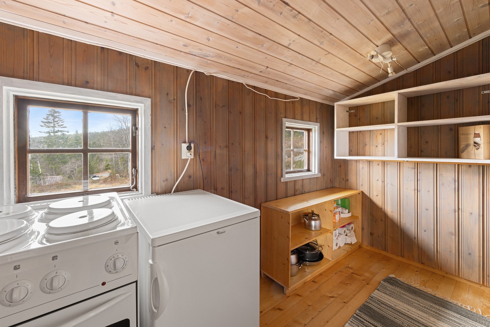 Frittstående hvitevarer som kjøleskap og komfyr stående i bod ved siden av kjøkkenet. Galleribilde