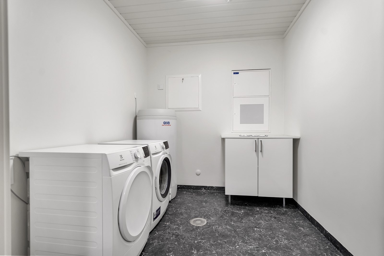 Praktisk vaskerom i forbindelse med badet med opplegg for vaskemaskin og tørketrommel, varmtvannsbereder og innredning Galleribilde