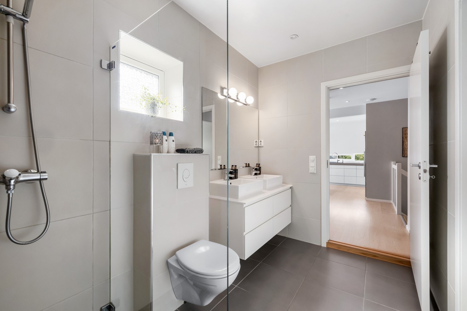 Stilrent uttrykk med store fliser på vegg og gulv og glassvegg som skjermer dusjsonen. Galleribilde