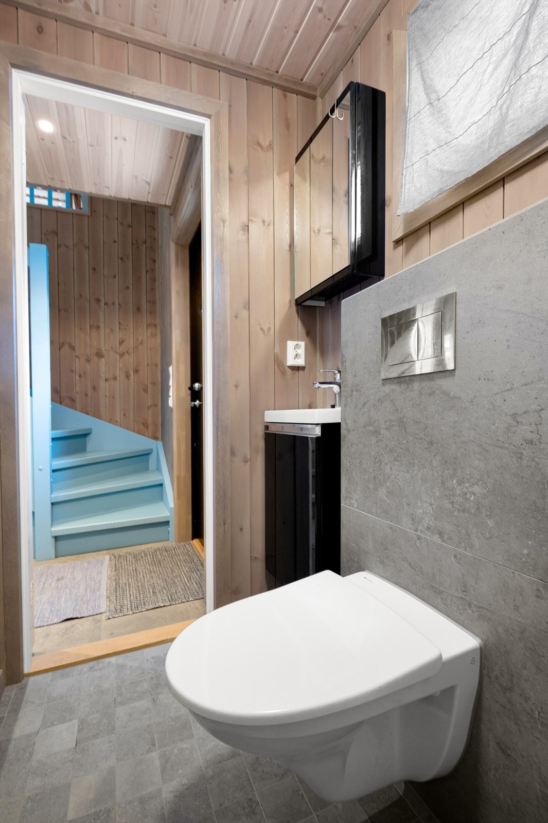 Toalettrommet inneholder servant med skuffeseksjon, speil, lys og vegghengt toalett Galleribilde