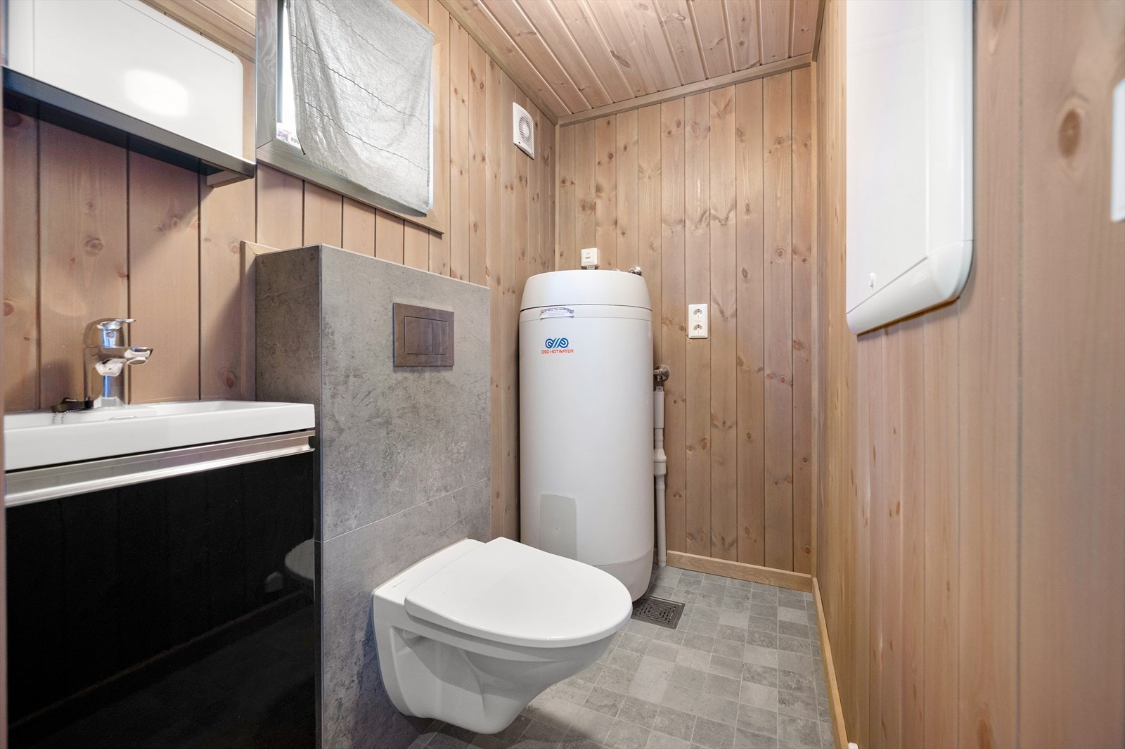 Flott separat toalettrom med varmtvannstank og opplegg for vaskemaskin Galleribilde