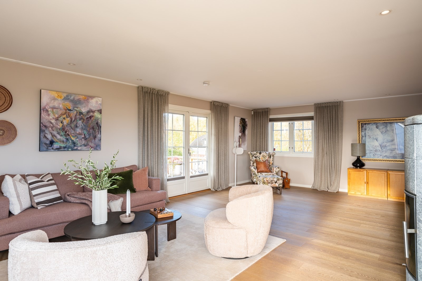 En tofløyet glassdør åpner stuen opp mot den solrike terrassen i front. Store vindusflater slipper inn rikelig med dagslys, og downlights i taket bidrar til en lun og moderne atmosfære. Galleribilde