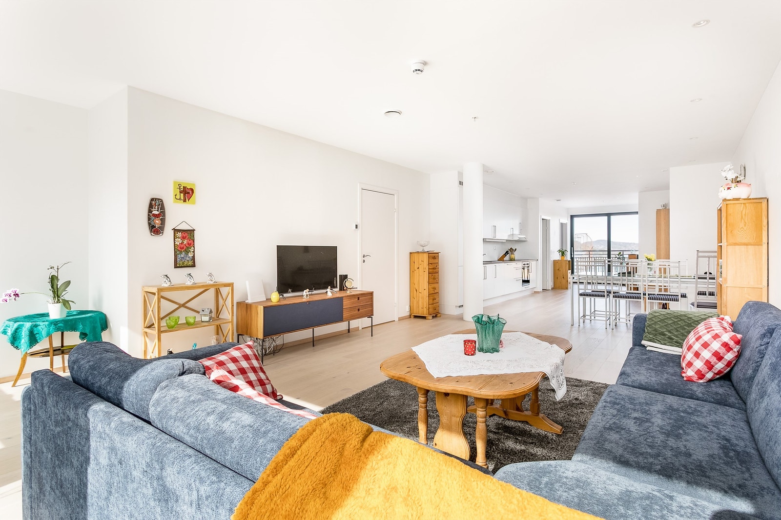 Stuen og kjøkkenet er sømløst forbundet i en langstrakt sosial sone med store vindusflater i begge ender. Galleribilde