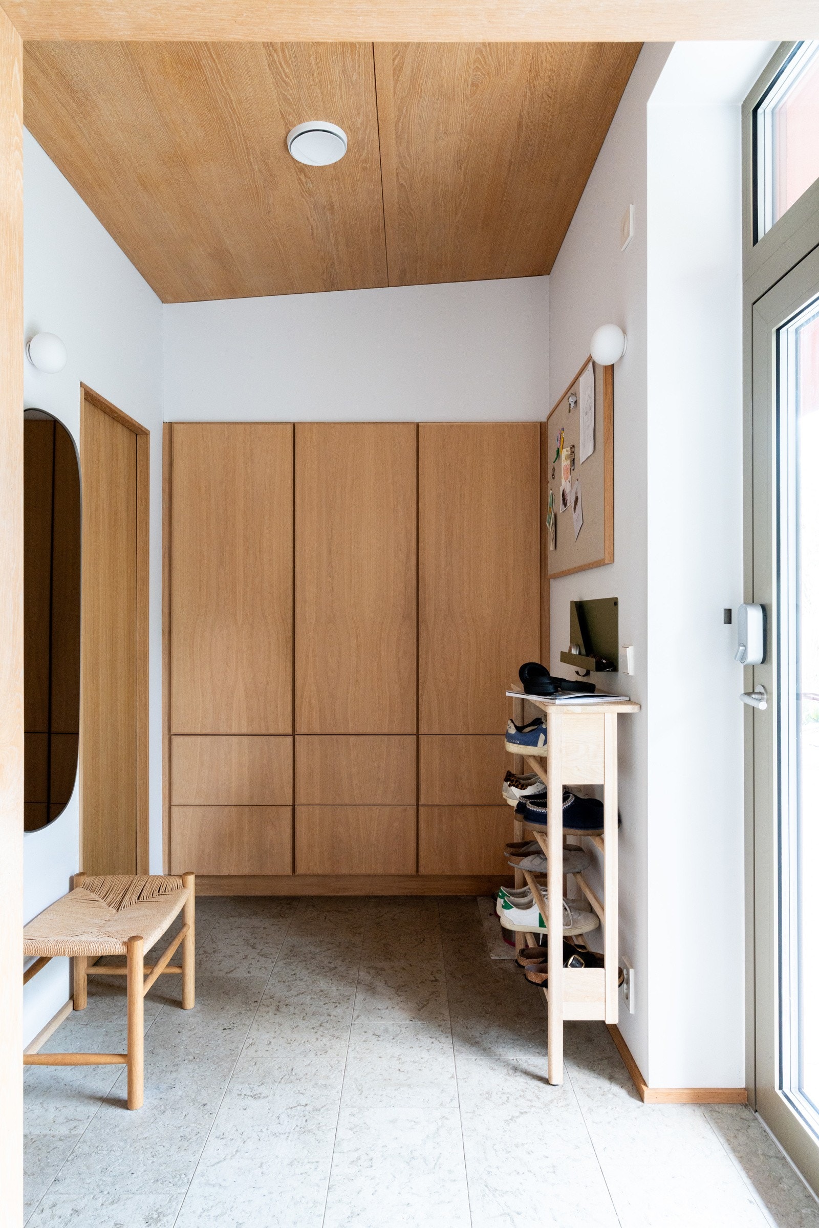 Boligens entre er lys og praktisk utformet med naturstenfliser i kalkstein på gulv, plassbygde garderobeskap i heltre eik som sammen med boden gir rikelig oppbevaringsplass.