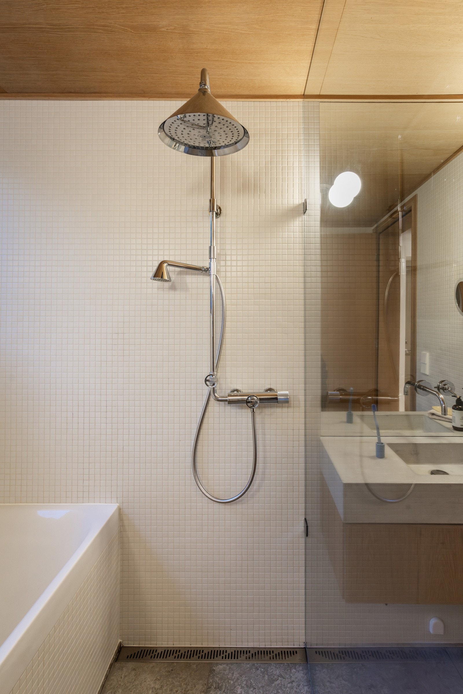 Gulvet er lagt med natursteinfliser og har vannbåren gulvvarme. Rommet er innredet med servantinnredning med nedfelt servant, dusjhjørne med glassvegger og et innbydende badekar plassert ved vinduet.