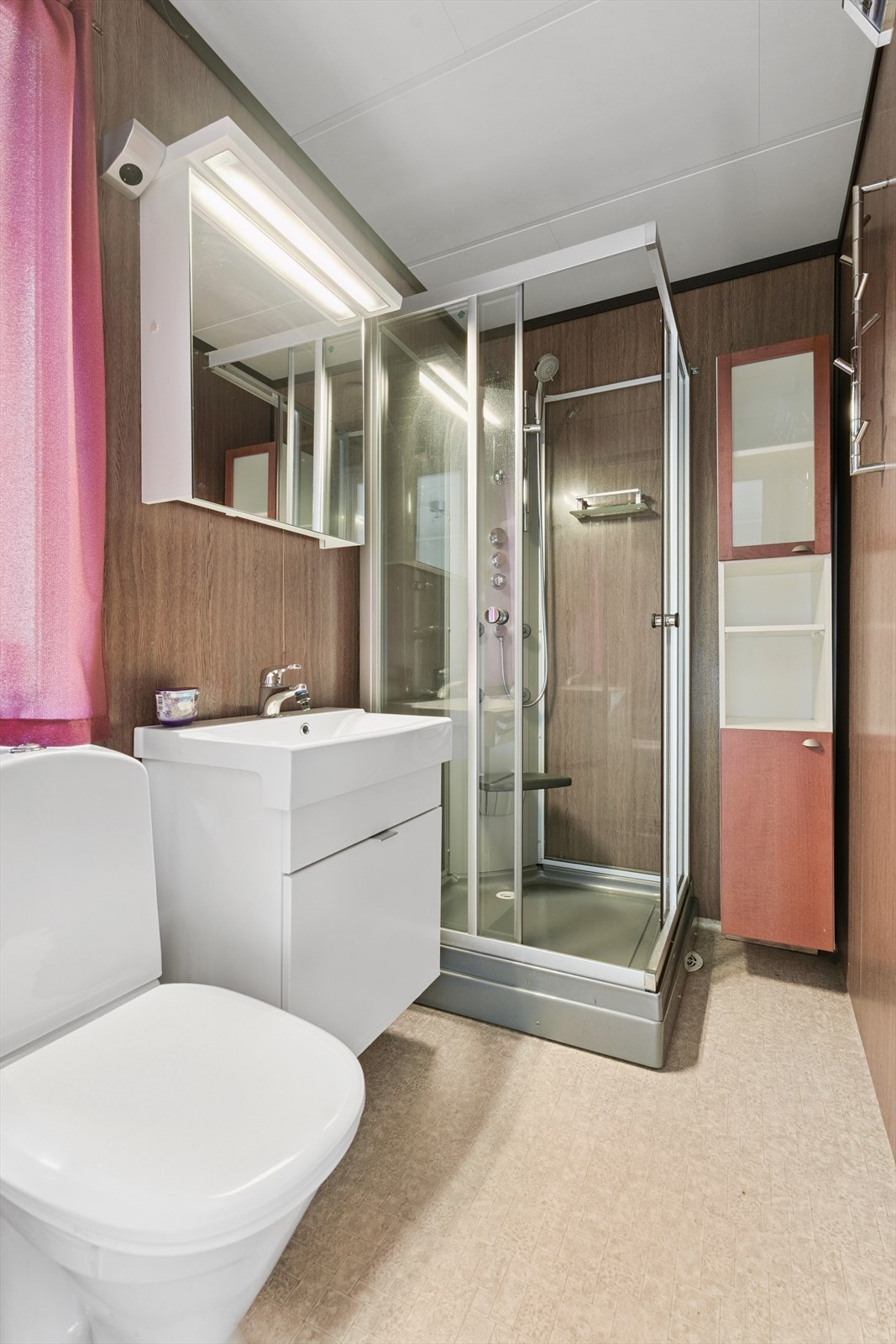Baderom i tilknytning til soverom III. Her har du servantinnreiing, dusjkabinett og golvståande toalett. Det er belegg på golv og plater på vegg. Galleribilde