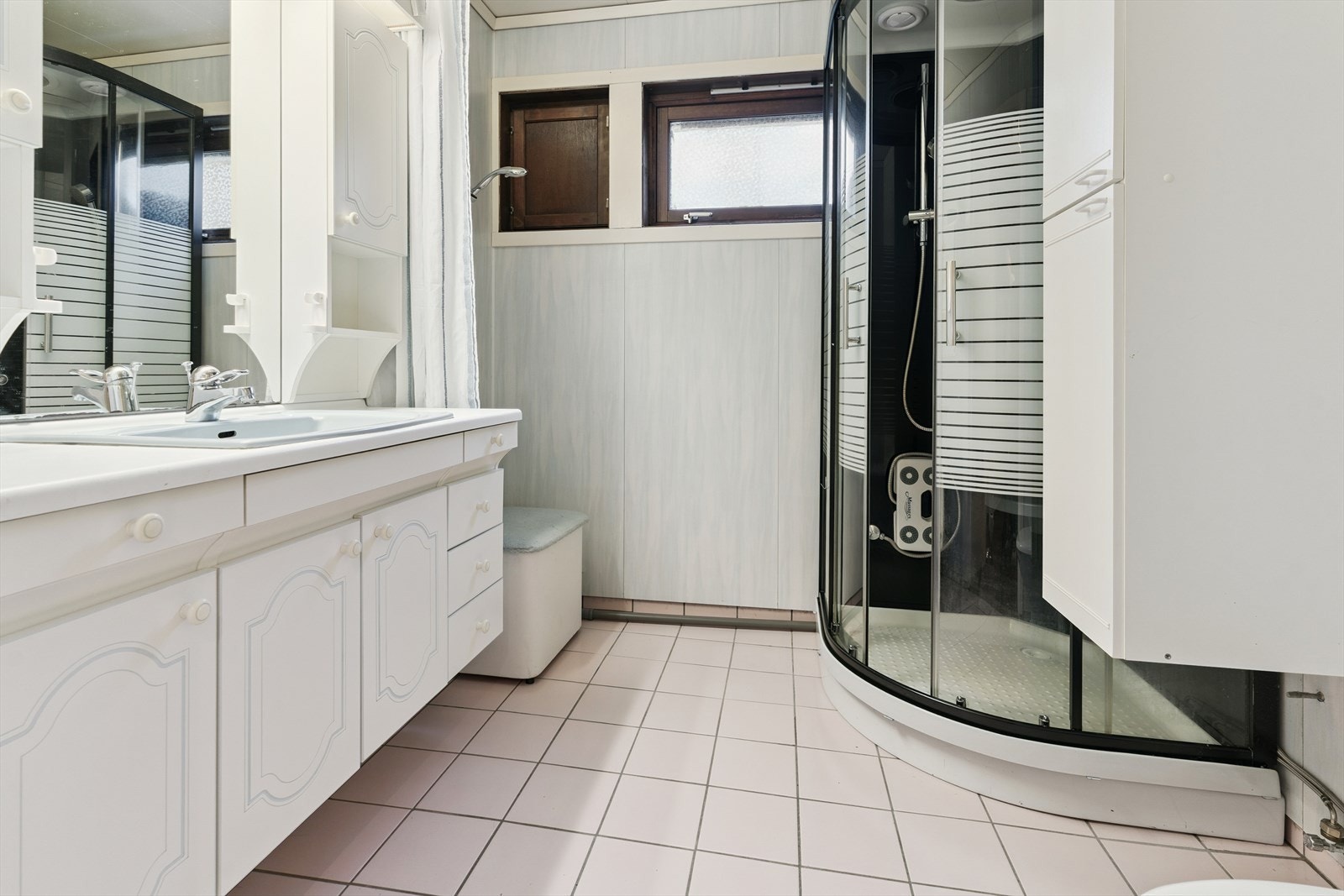 Bad i underetasje med flis på golv med varmekablar. På veggar er det baderomsplater. Du har servantinnreiing med nedfelt servant, golvståande toalett og dusjkabinett. Galleribilde