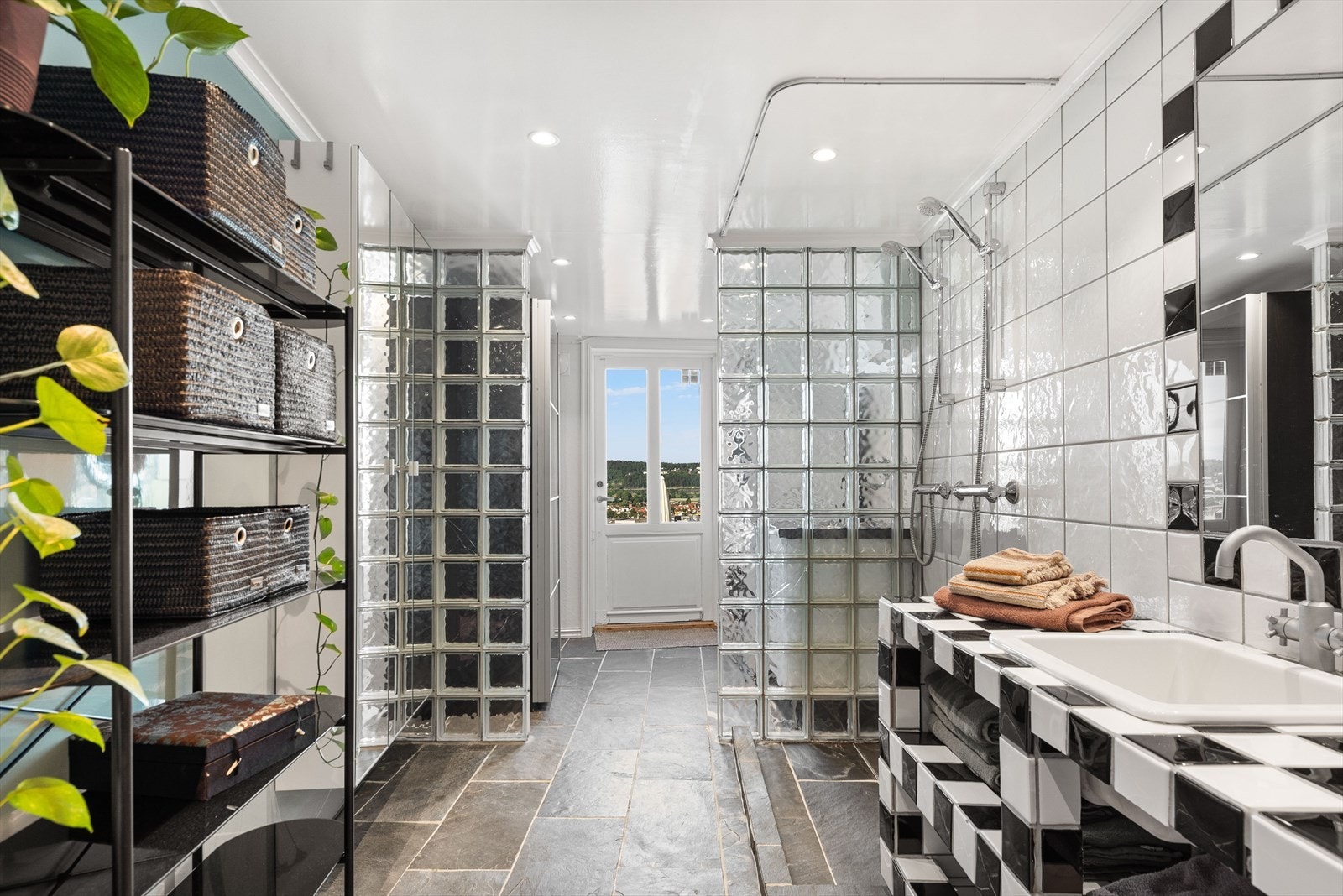 Badet er pusset opp i 2001 og inneholder veggmontert toalett, servant med flislagt innredning, speil, veggmontert dobbeldusj med glassbyggerstein og forheng. Galleribilde