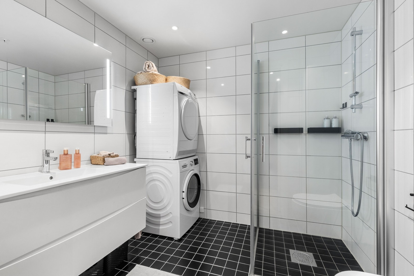 Leiligheten har to bad ved gangen, der hvite veggfliser og sorte mosaikkfliser på gulvet gir en fin kontrast. Galleribilde