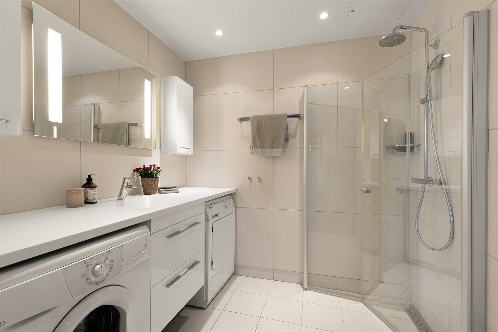 Baderom med varmekabler på gulv. Rikelig med oppbevaring i over- og underskap. Opplegg for vaskemaskin. Galleribilde