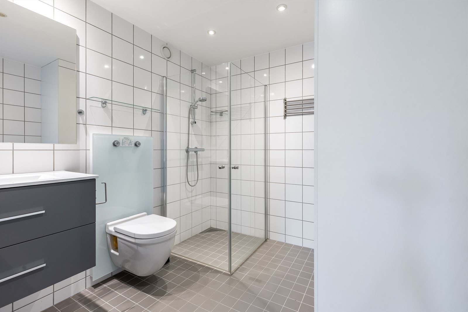 Lyst og fint flislagt bad med varmekabler i gulv og spotter i tak Galleribilde