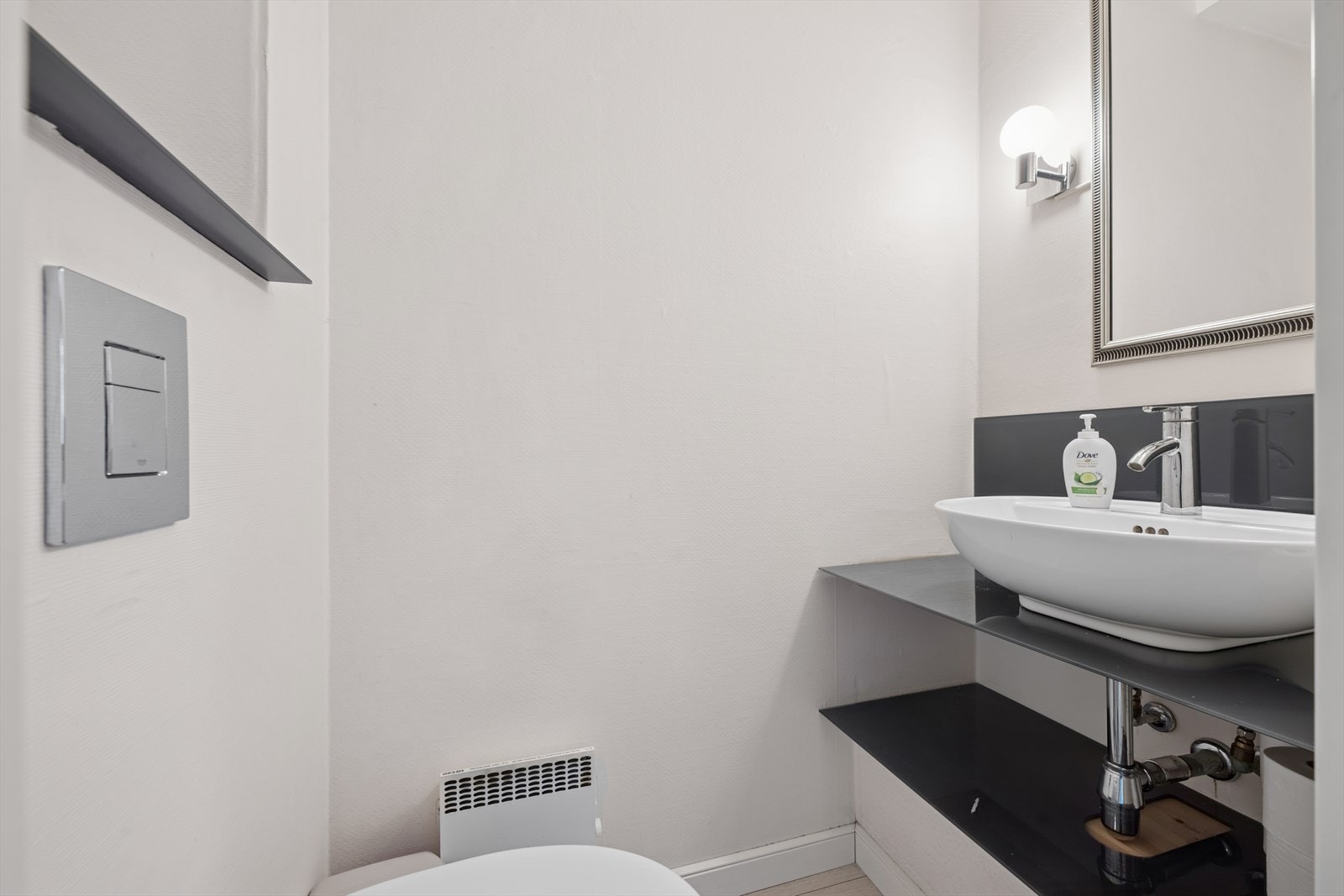 I boligens første etasje er det også et praktisk og stilrent toalettrom, perfekt egnet som gjestetoalett. Rommet er innredet med funksjonell baderomsinnredning, inkludert toalett, servant og speil. Galleribilde
