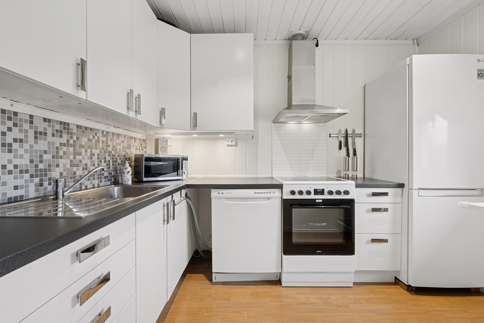 Praktisk og innbydende kjøkken med lyse slette fronter og laminert benkeplate med oppvaskkum. Galleribilde