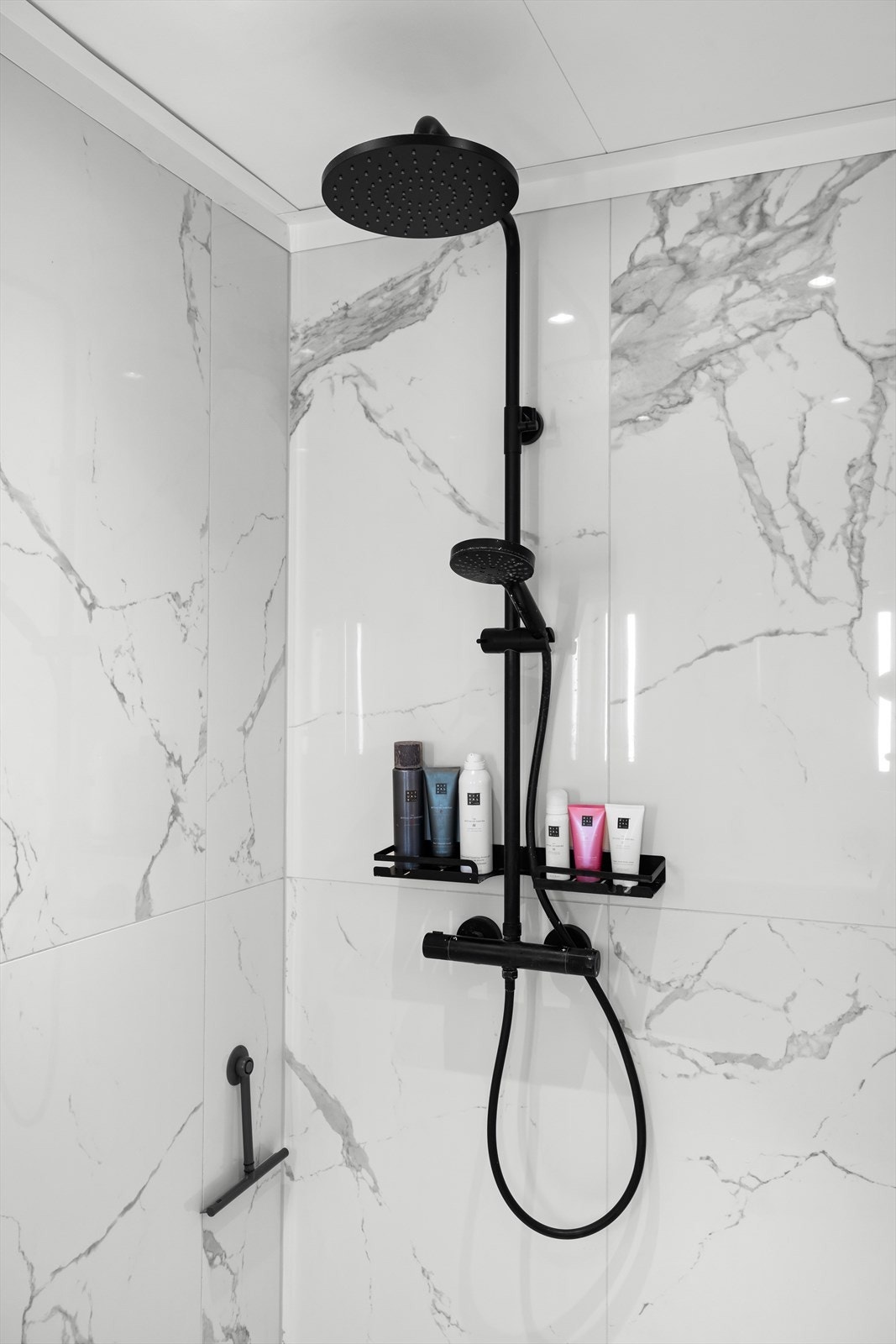 Dusjarmaturet er utført i en moderne, sort finish som komplementerer flisvalget. Galleribilde