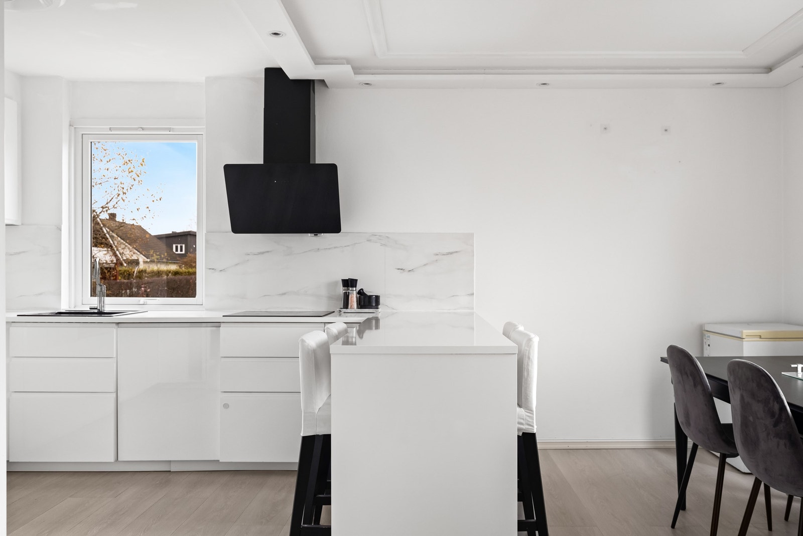 Innredningen har glatte, hvite fronter og en stilren, mørk ventilator. Galleribilde