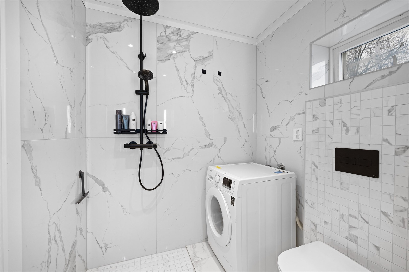 Rommet er utstyrt med vegghengt toalett, dusjhjørne og opplegg for vaskemaskin. Galleribilde