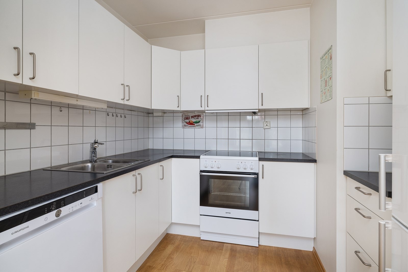 Lyst kjøkken med glatte fronter og laminat benkeplate. Galleribilde