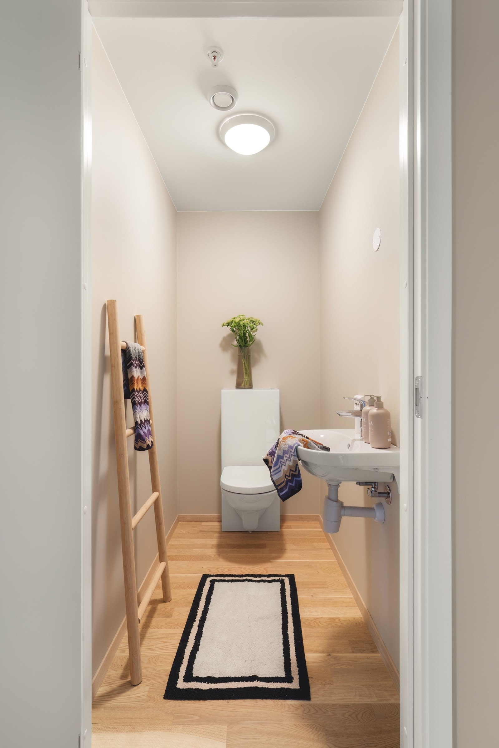 Leiligheten har i tillegg et praktisk gjestetoalett, utstyrt med vegghengt toalett, enkel baderomsinnredning og speil. Galleribilde