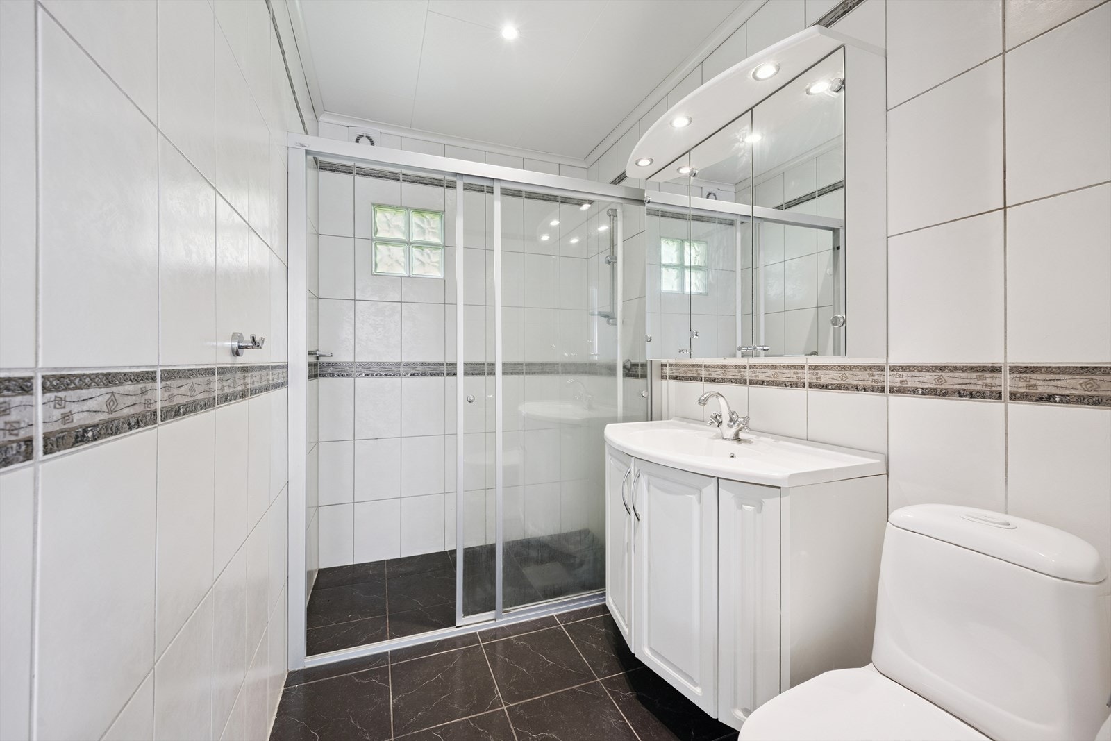 Fliselagt bad med varmekabler i gulv. Innredet med baderomsinnredning, toalett og dusjløsning. Galleribilde