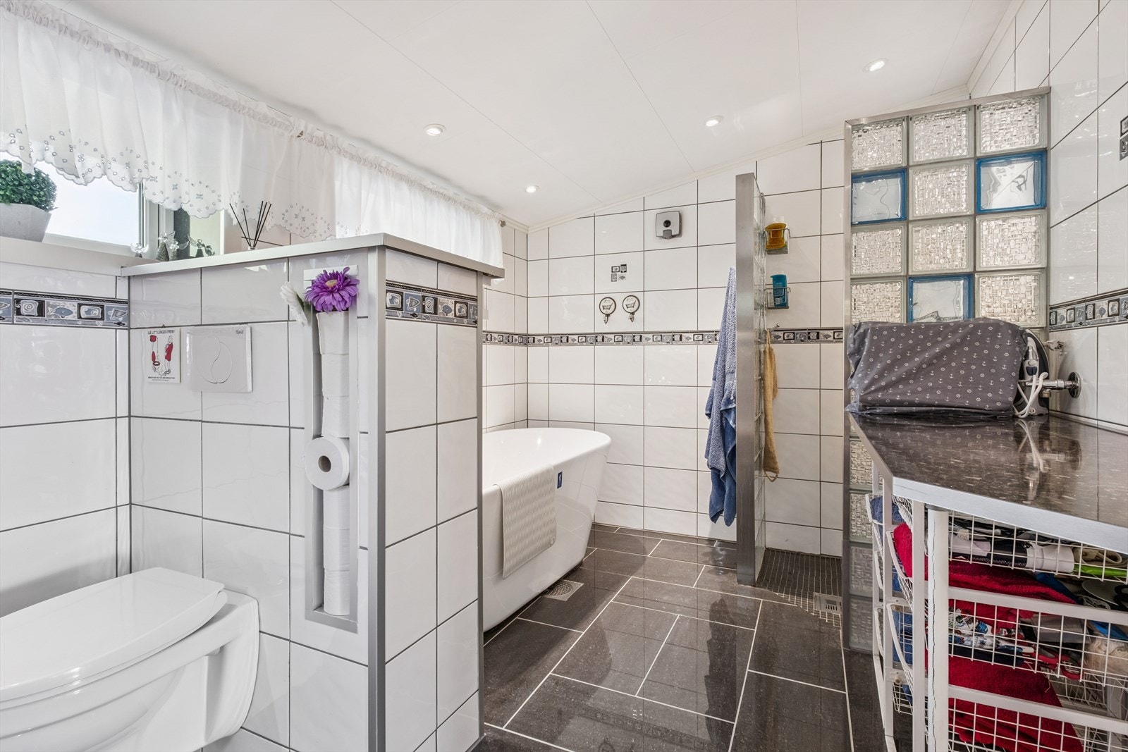 Her får man et flislagt bad med gulvvarme, vegghengt toalett, badekar og dusjnisje Galleribilde