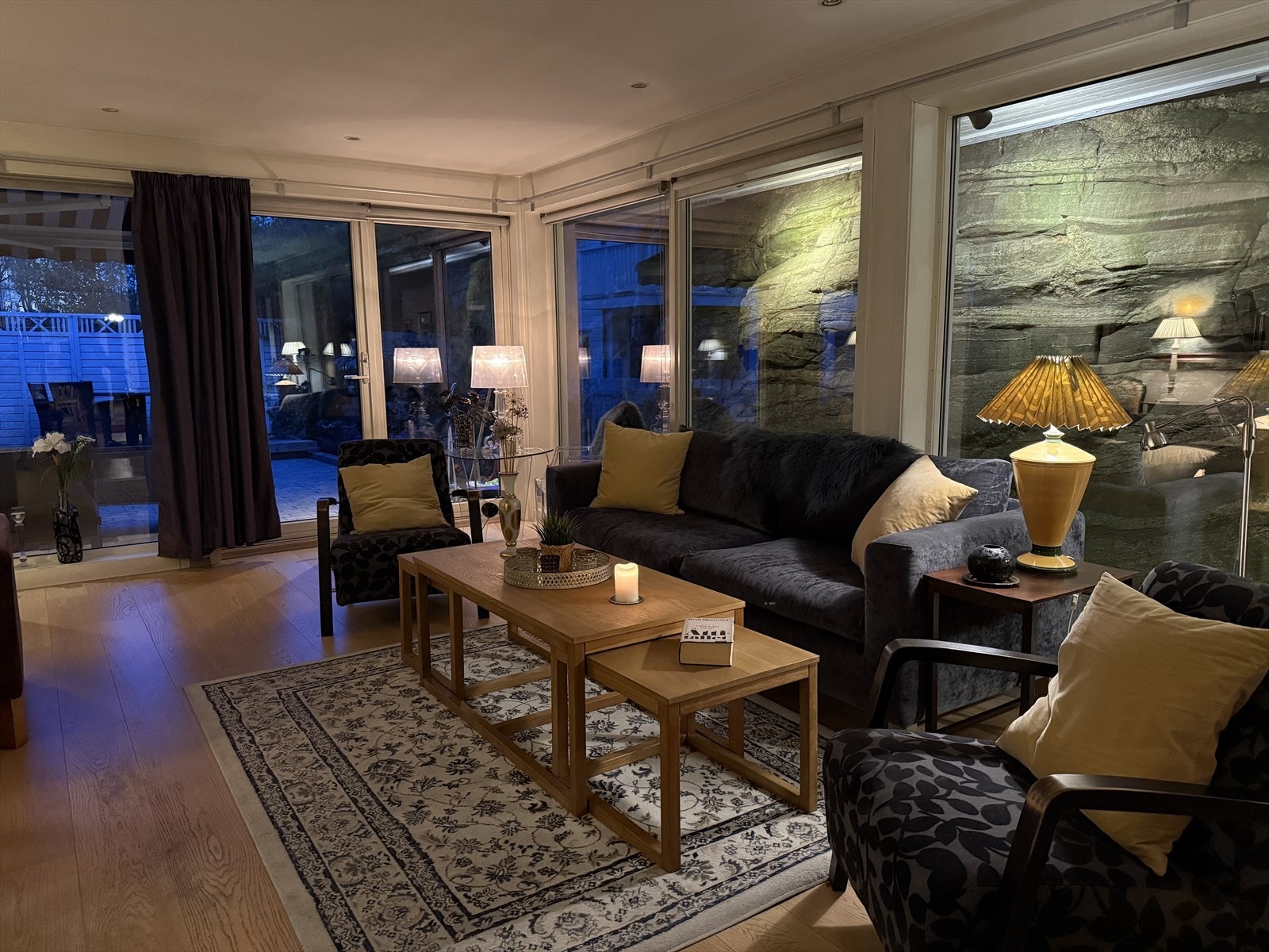 Utenfor er fjellsiden opplyst av utelamper som gir et unikt og lekkert motiv inn til stuen. Galleribilde