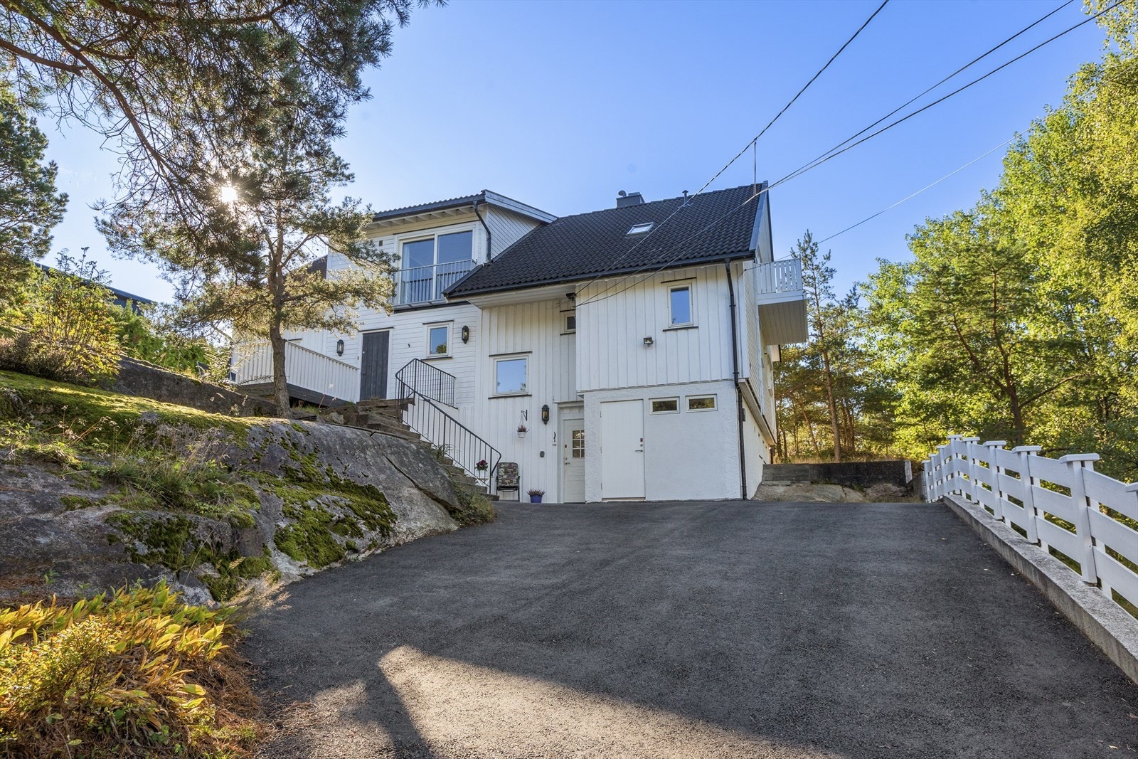 Oppkjørsel med plass til flere biler. Det er montert elbil-lader i husveggen. Det er også opparbeidet ekstra parkeringsplass nedenfor tomten langs veien Galleribilde