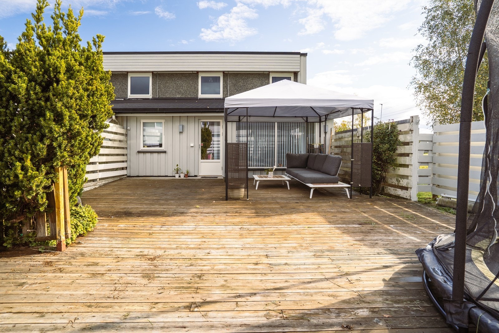 Romslig terrasse med god plass til både spisegruppe og trampoline. Galleribilde