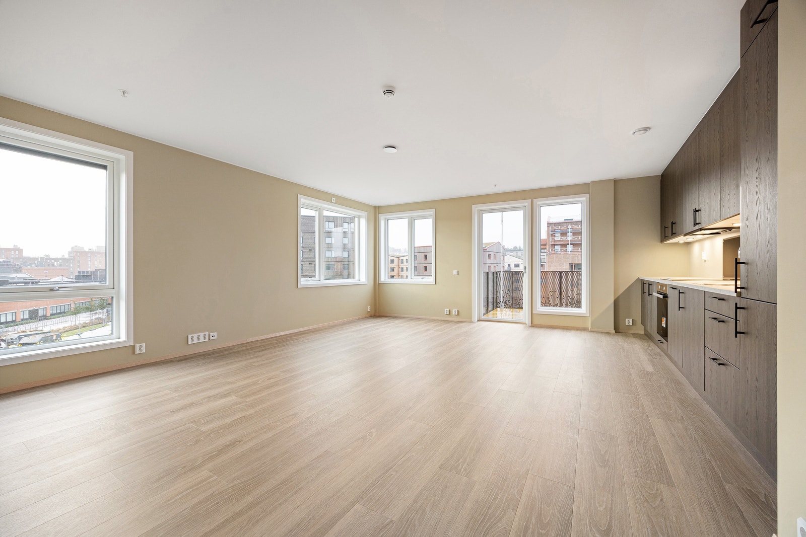 Stue med åpen kjøkkenløsning og store vindusflater som slipper inn naturlig dagslys Galleribilde