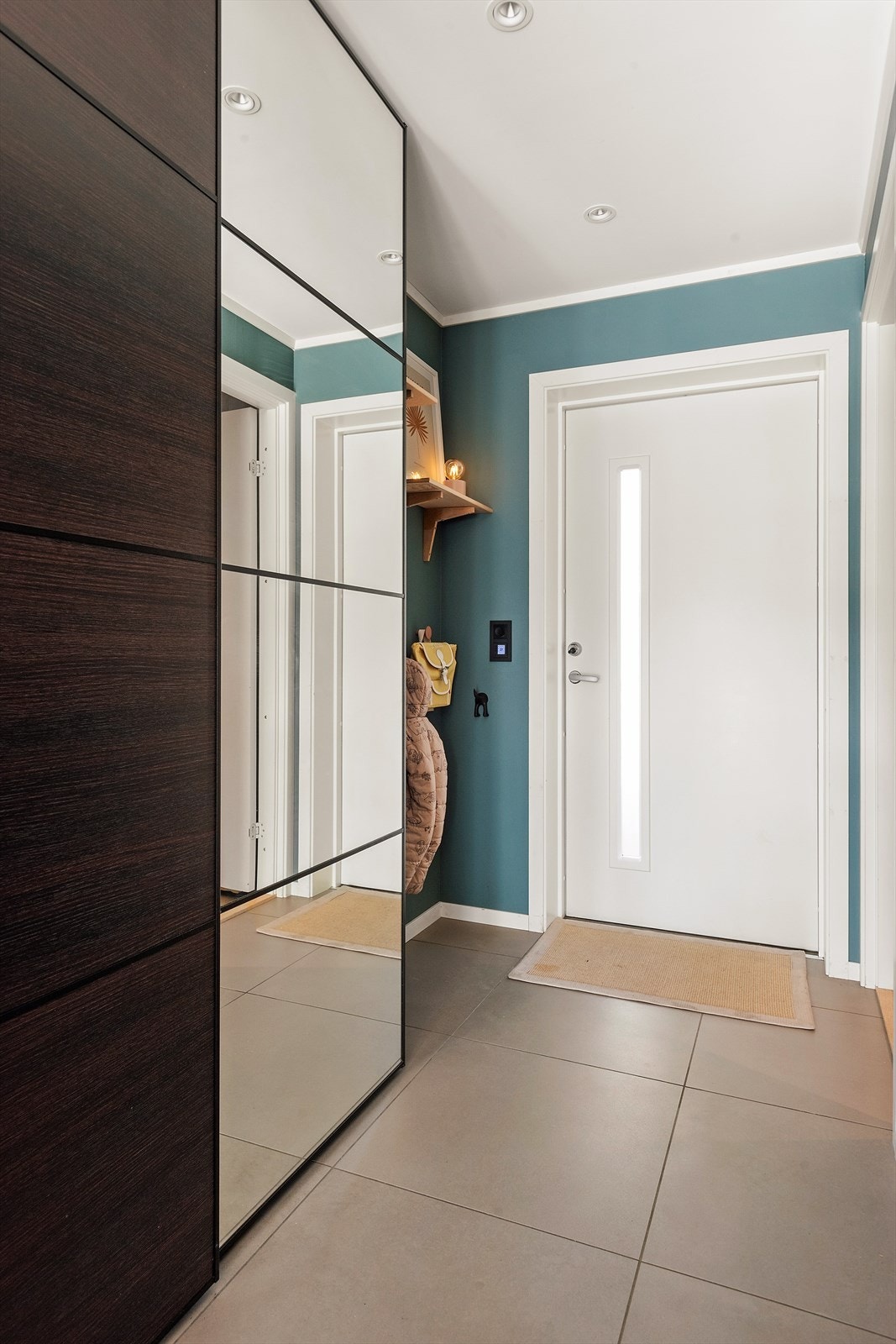 Velkommen inn! Legg merke til de store fine flisene og skyvedørsgarderoben med speilfronter. Spotter i tak. Galleribilde