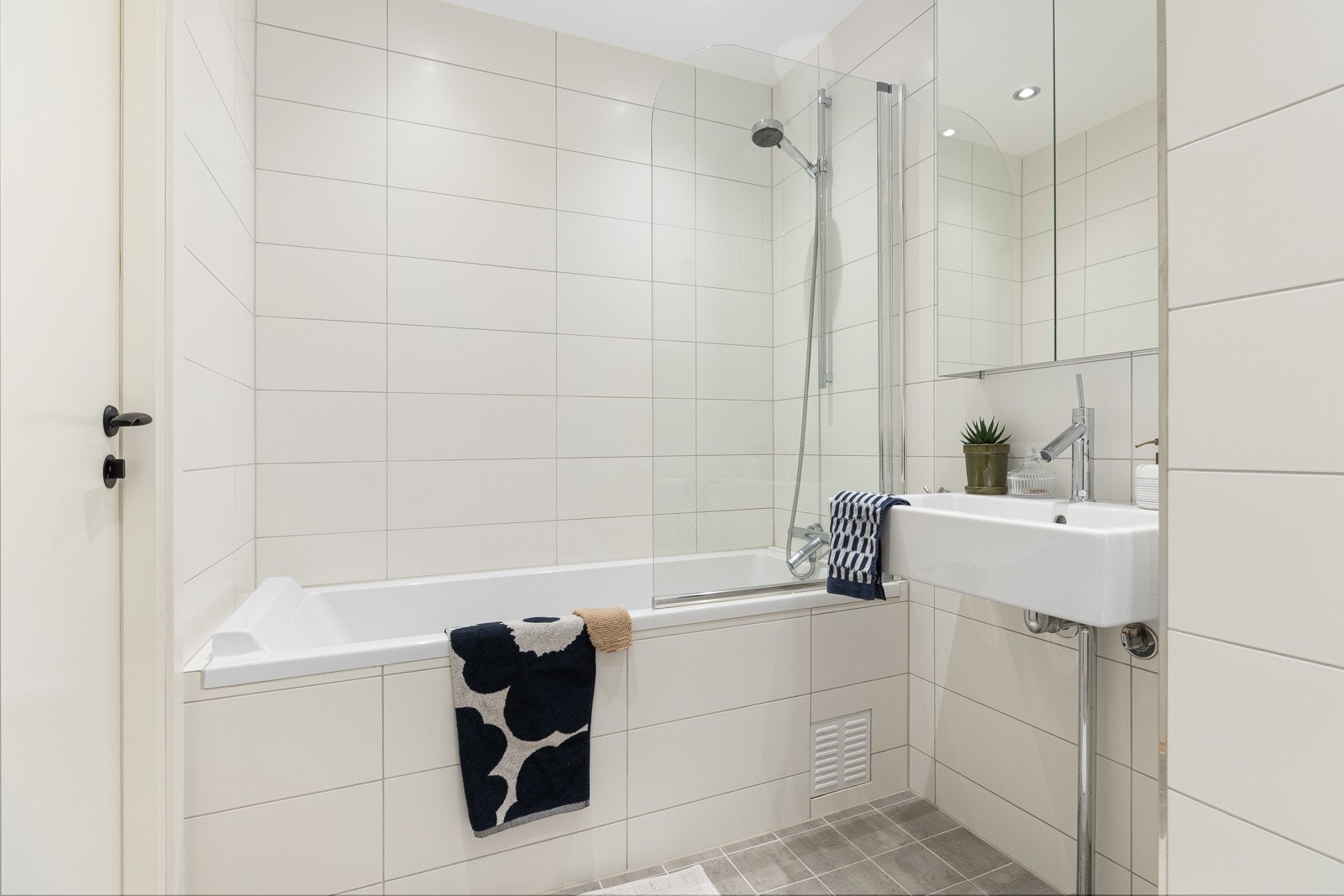 Flislagt gulv fra 2020(flis-på-flis). Det er av fin størrelse og har vegghengt toalett, servant med speilskap og badekar med dusjarmatur Galleribilde