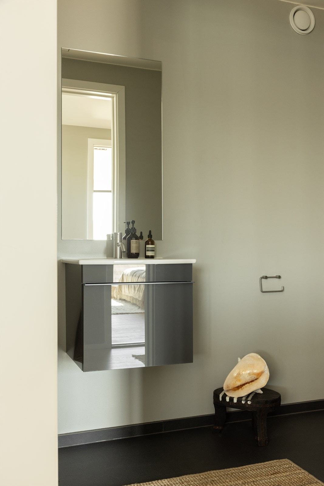 Separat gjestetoalett ved entré, med flislagt gulv, vegghengt toalett, servant med møbel og speil. Praktisk og delikat utformet. Galleribilde