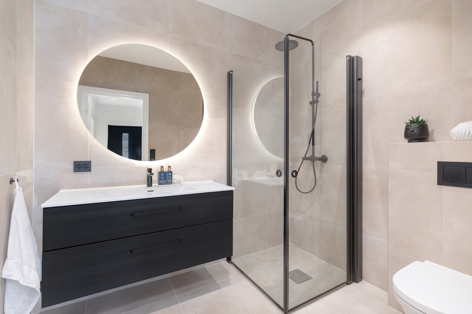 Baderommet er lekkert flislagt med varme i gulv. På badet er det servant med oppbevaring, toalett, og dushjørne Galleribilde