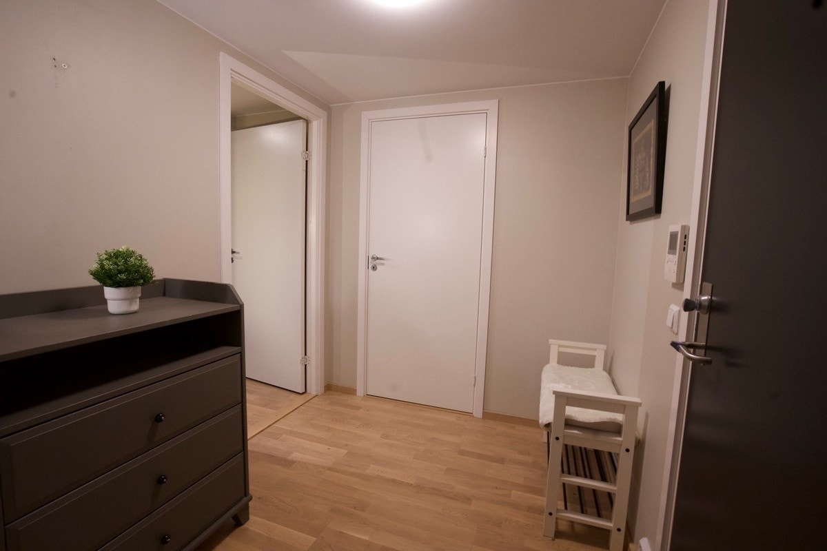 Entré med lyse vegger og samme trestavs eikeparkett som i resten av leiligheten, skaper en helhetlig og gjennomført stil. Galleribilde