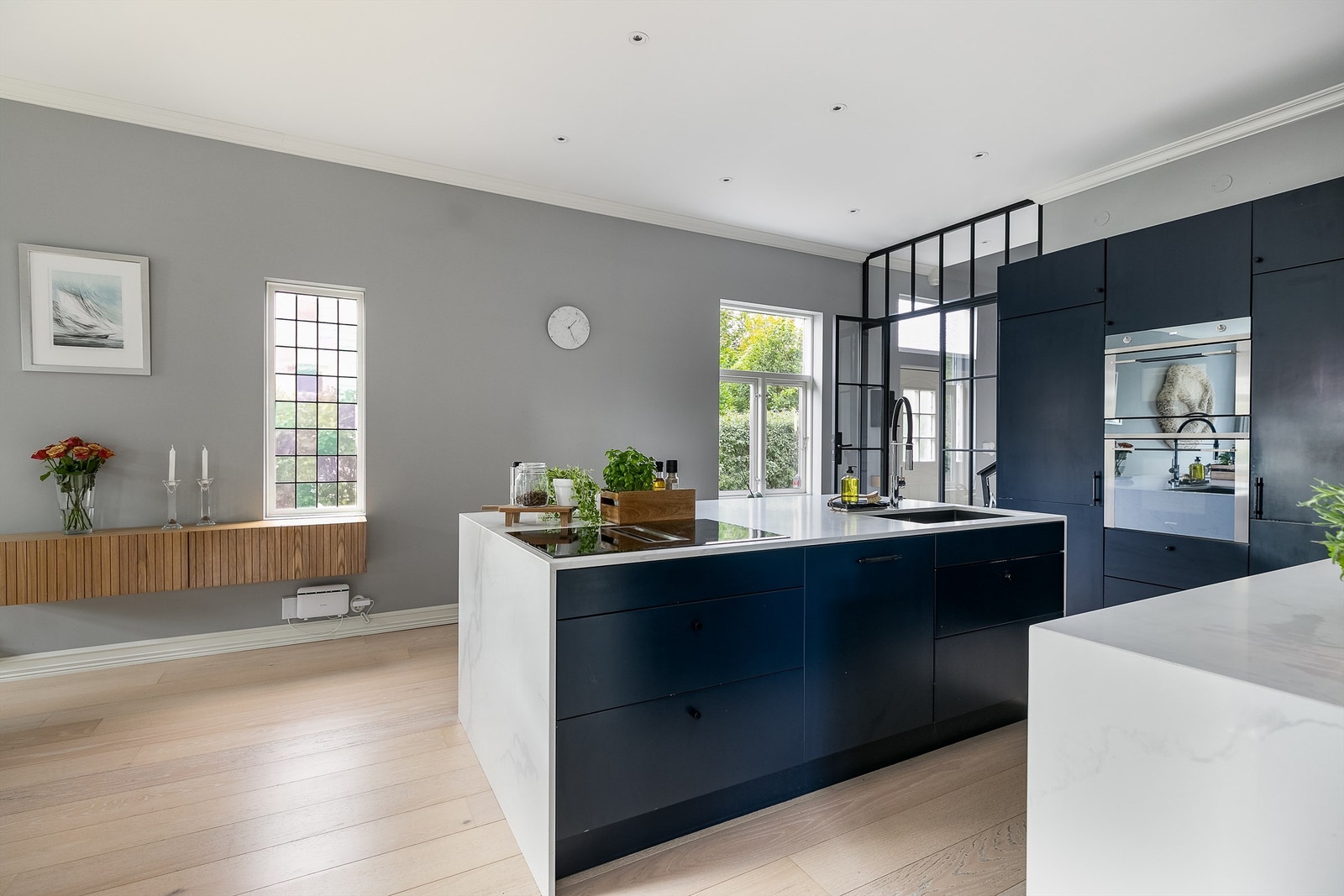 Kjøkkeninnredningen har stilsikker fremtoning med sorte Picky Living knotter samt Calacatta Silestone benkeplater og dekksider. Galleribilde