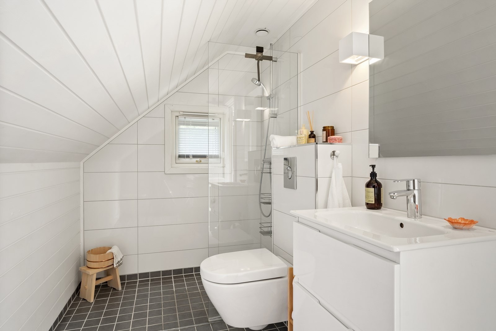 Bad i 2. etasje har flislagte overflater på både gulv og 2 vegger samt panel på resterende vegger.
Rommet er innredet med baderomsmøbel med nedfelt servant, slette og lyse fronter, samt overhengende speil med belysning. Galleribilde