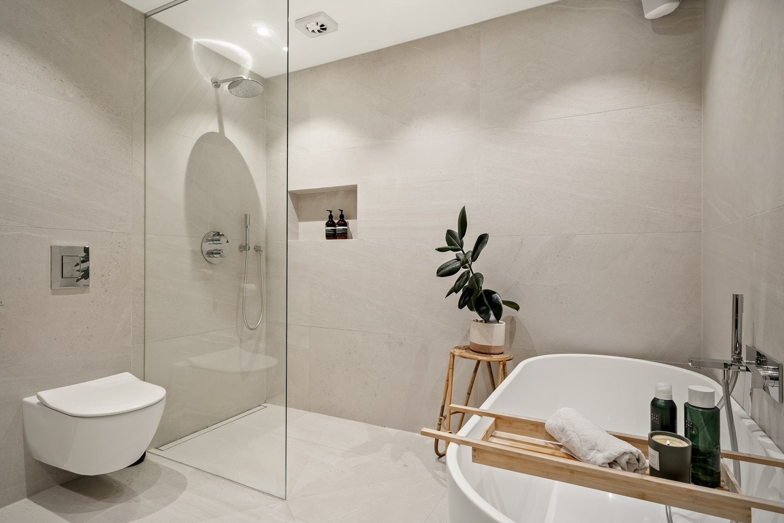 Dusj sonen er plassert i hjørnet og er utstyrt med fastfelt i glass og innebygd dusjarmatur med regndusj samt slukrenne.
Videre er det installert vegghengt toalett og frittstående badekar med innebygd badekarsarmatur. Galleribilde