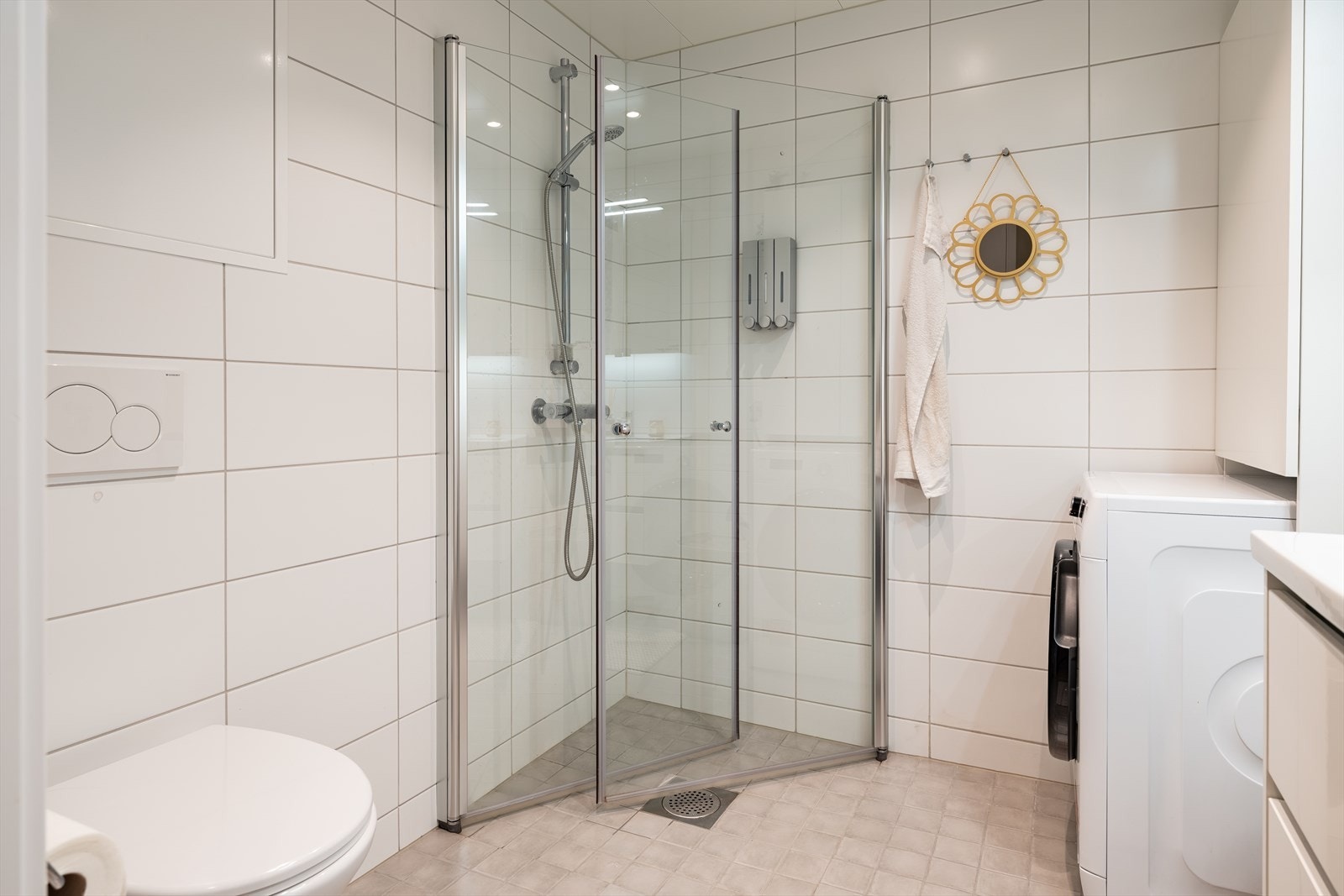 Badet er utstyrt med servant, servantskap, mekanisk avtrekk, veggmontert wc, innfellbare dusjdører og opplegg for vaskemaskin. Galleribilde