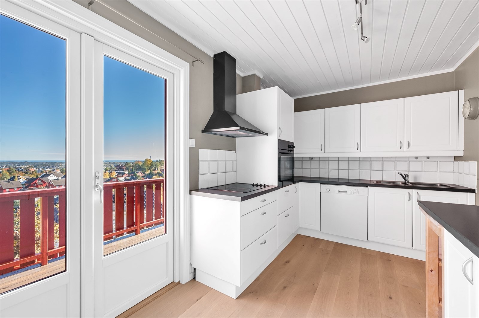 Kjøkken med hvite fronter, delvis integrerte hvitevarer og utgang til veranda. Galleribilde