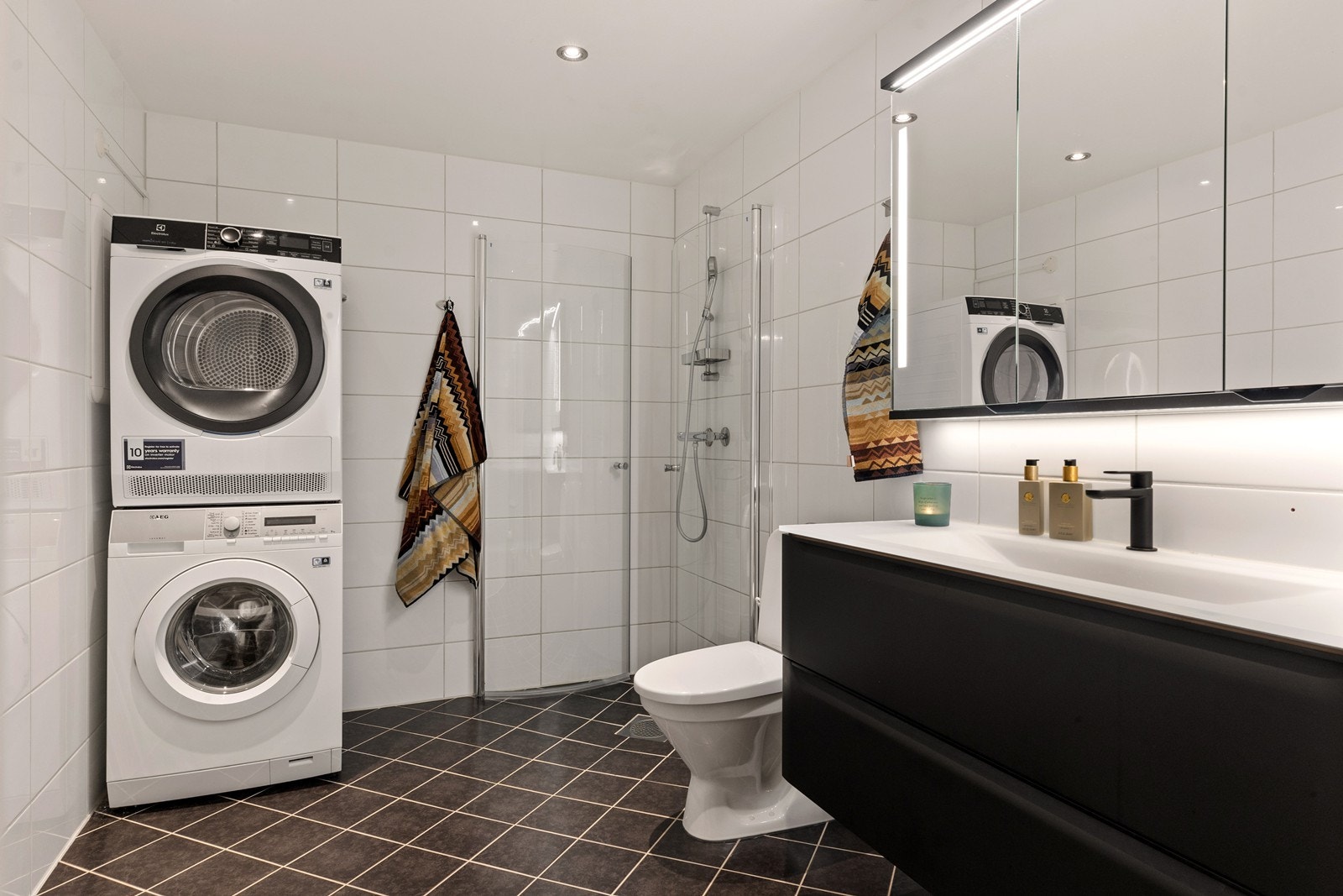 Badet er flislagt med varmekabler i gulvet. Gulvmontert wc, dusjnisje med innfellbare glassdører og baderomsinnredning fra -22. Galleribilde