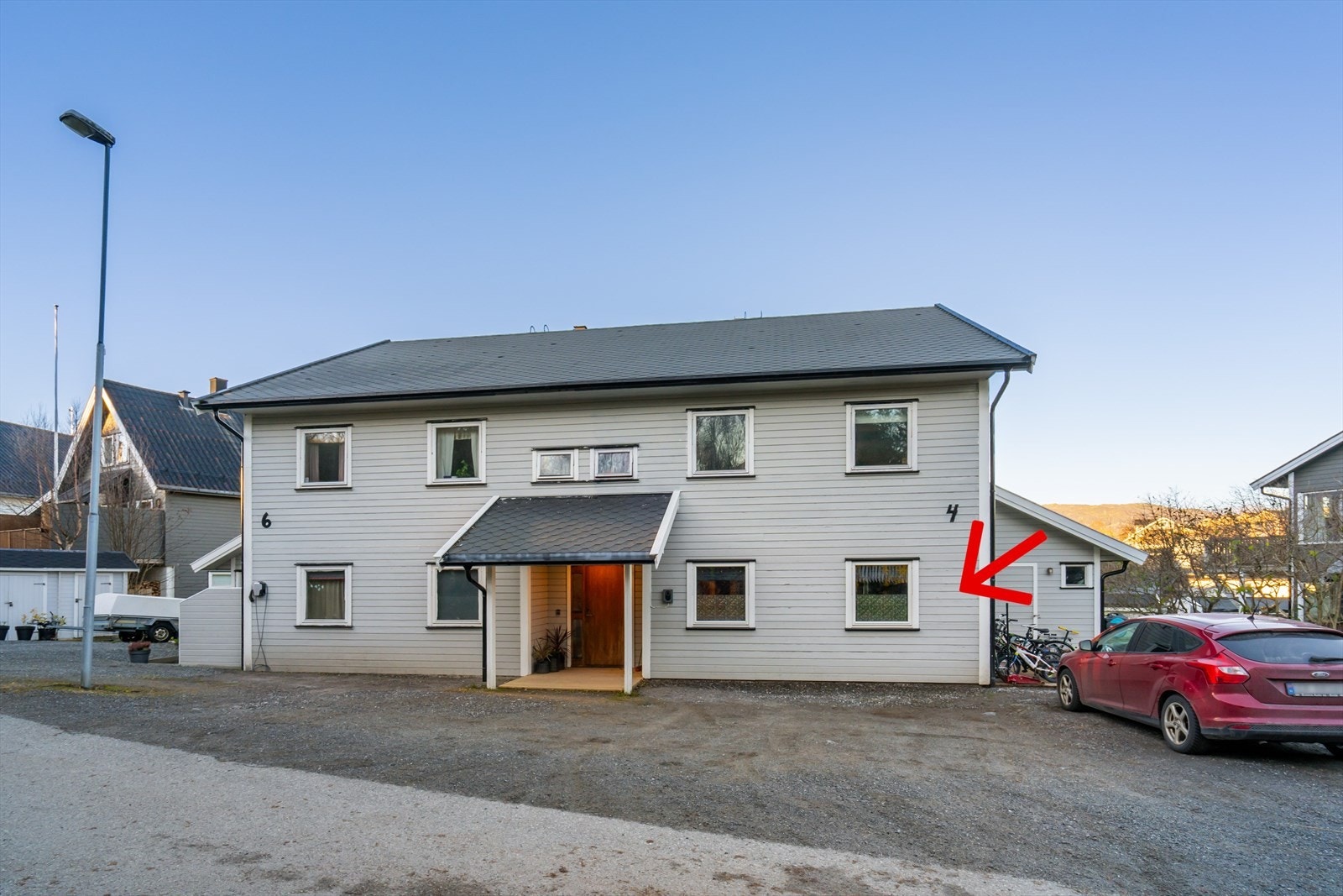 Framsiden av huset med gruset parkeringsareal i front, hvor det disponeres 2 parkeringsplasser Galleribilde