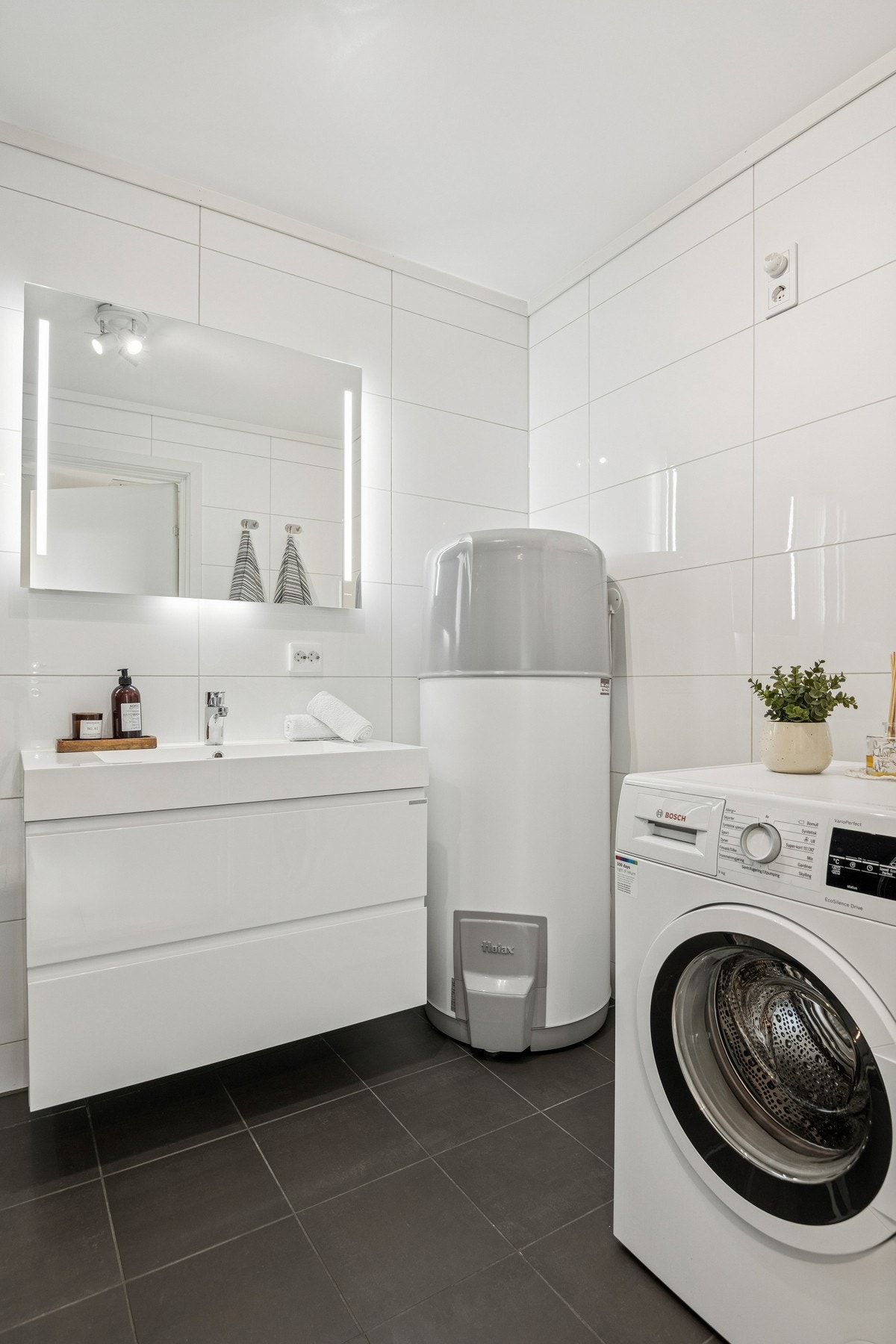 Opplegg for vaskemaskin er praktisk plassert, og god belysning fra downlights i himling gir et rent og tidløst uttrykk. Galleribilde