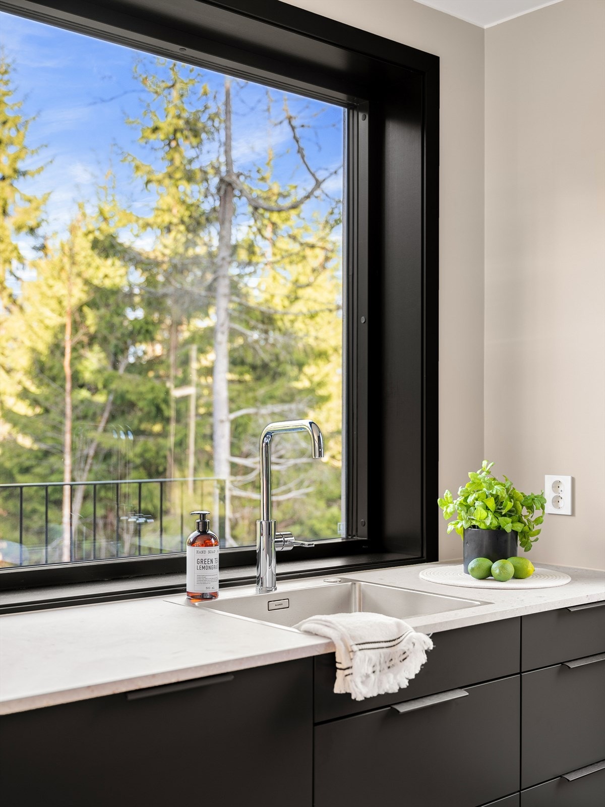 Kjøkkenet har mørke, slette fronter og Terrazzo 20 mm laminat benkeplate med nedfelt oppvaskkum Galleribilde