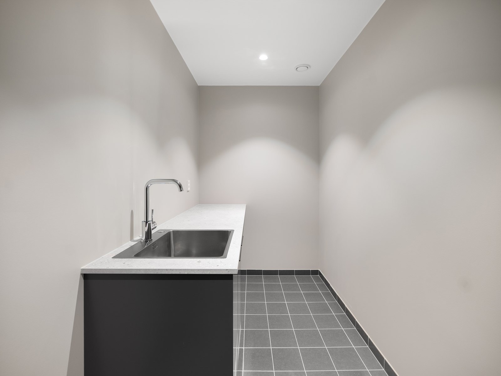 Praktisk vaskerom i kjelleretasje med flislagt gulv og malte veggflater Galleribilde