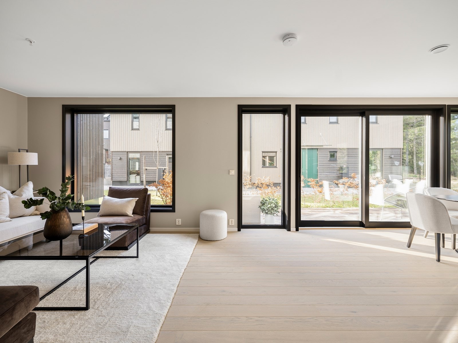 Lys og luftig stue med store vindusflater. Skyvedør ut til hyggelig uteareal som boligen har eksklusiv bruksrett til Galleribilde