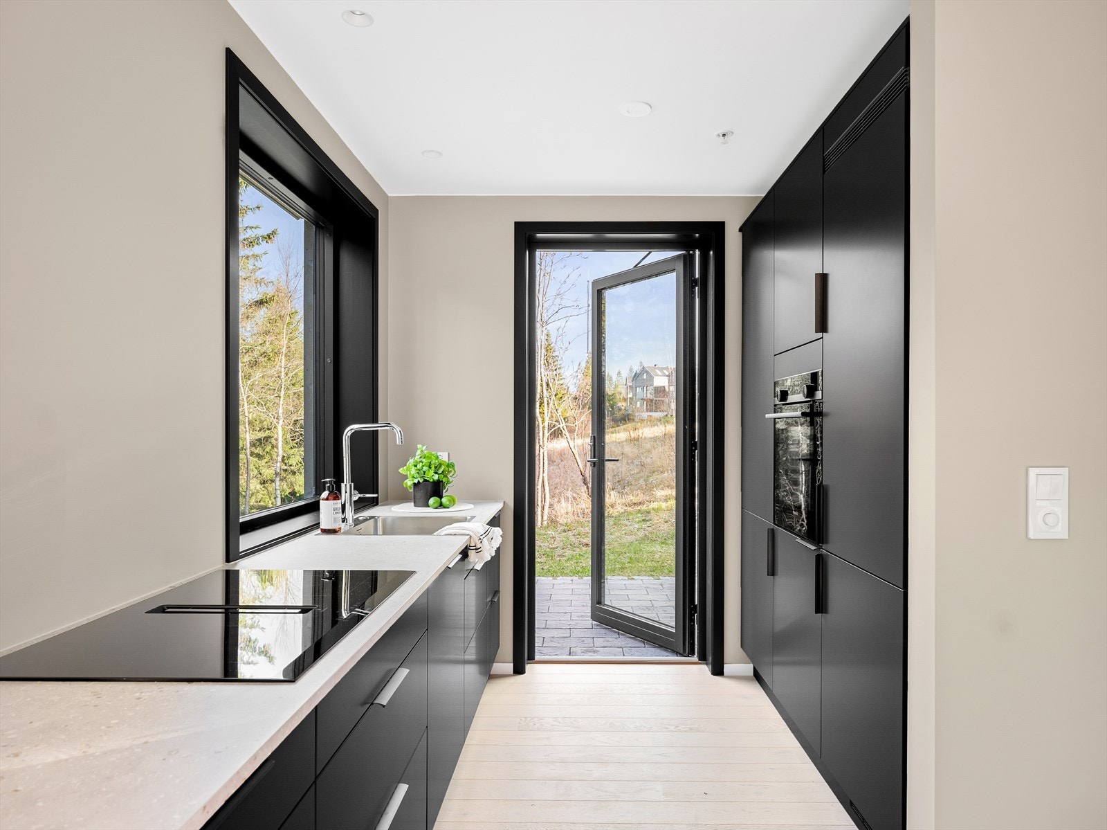 Kjøkkenet får masse lys fra store vindusflater og har direkte utgang terreng, en fin uteplass med belegningsstein Galleribilde