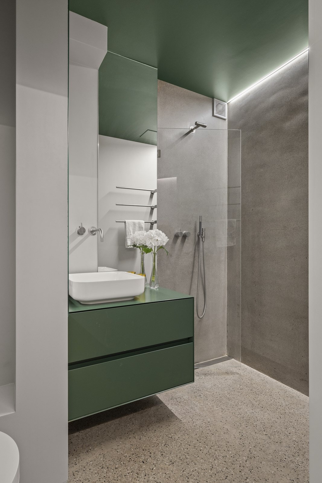 Pent baderom med sementpussede vegger i dusjsonen. Gulvet er slipt betong. Galleribilde